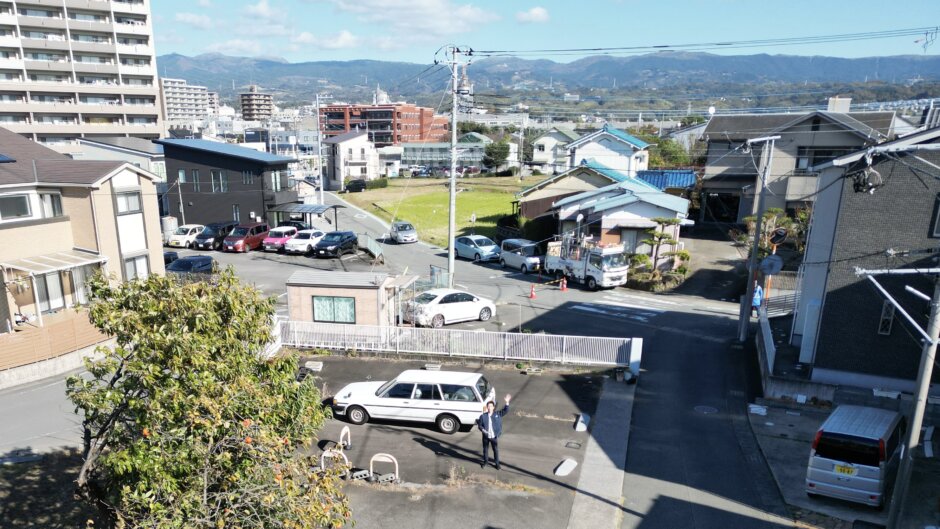 三島市青木エリアの住宅街の風景｜住宅やマンション、駐車場が並び、背景に山々が広がる街並み